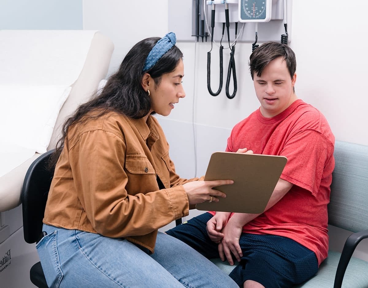 Man with Down syndrome sitting with clinical coordinator looking at a clipboard