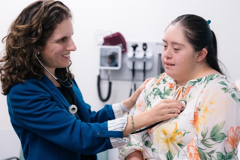 Physician listening to a patient with Down syndrome's heart with a stethoscope