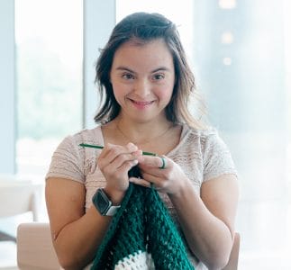 Woman with Down syndrome smiling and knitting