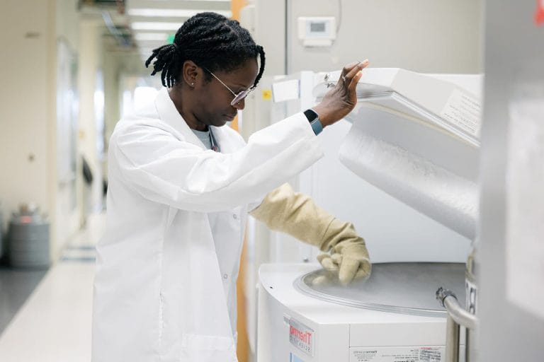 Scientist in a lab coat getting Down syndrome biospecimens out of a freezer