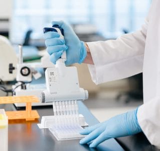 Down syndrome scientist wearing gloves and using a multichannel pipet to process biological samples