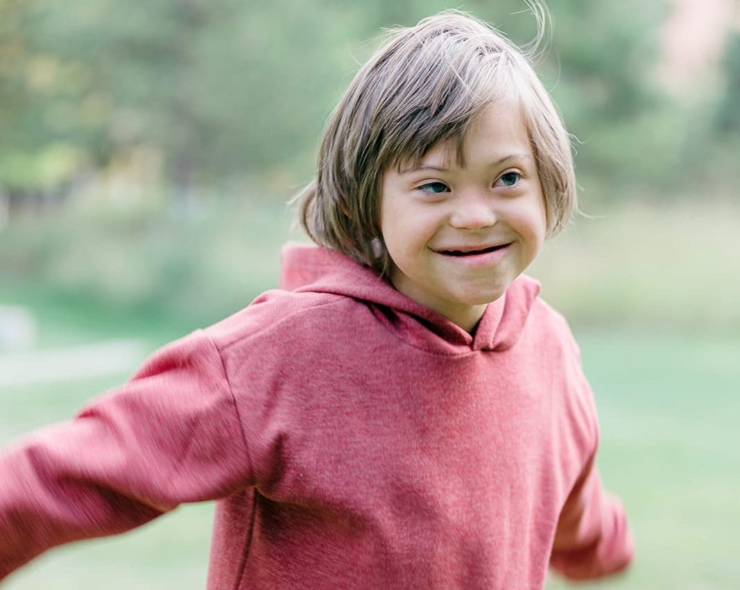 Young boy with Down syndrome running and smiling