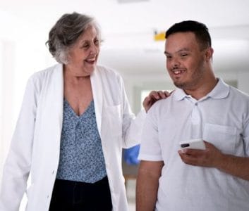 Scientist in a lab coat walking with a man with Down syndrome