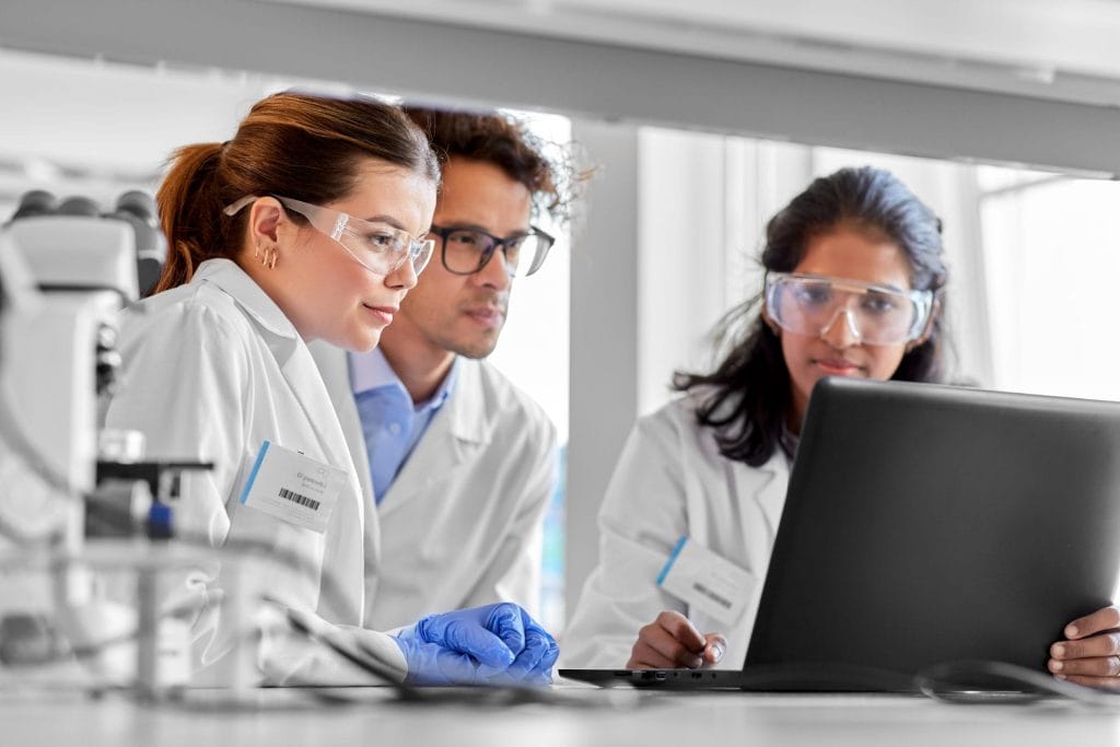 Three scientists looking at a laptop in a lab