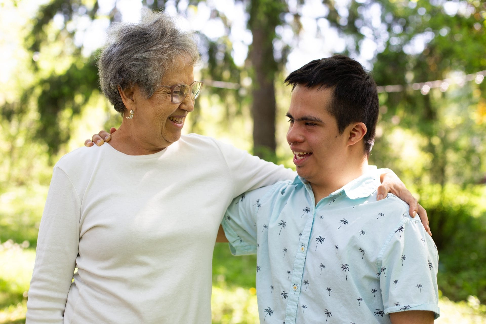 Man with Down syndrome smiling with his arm around an older woman